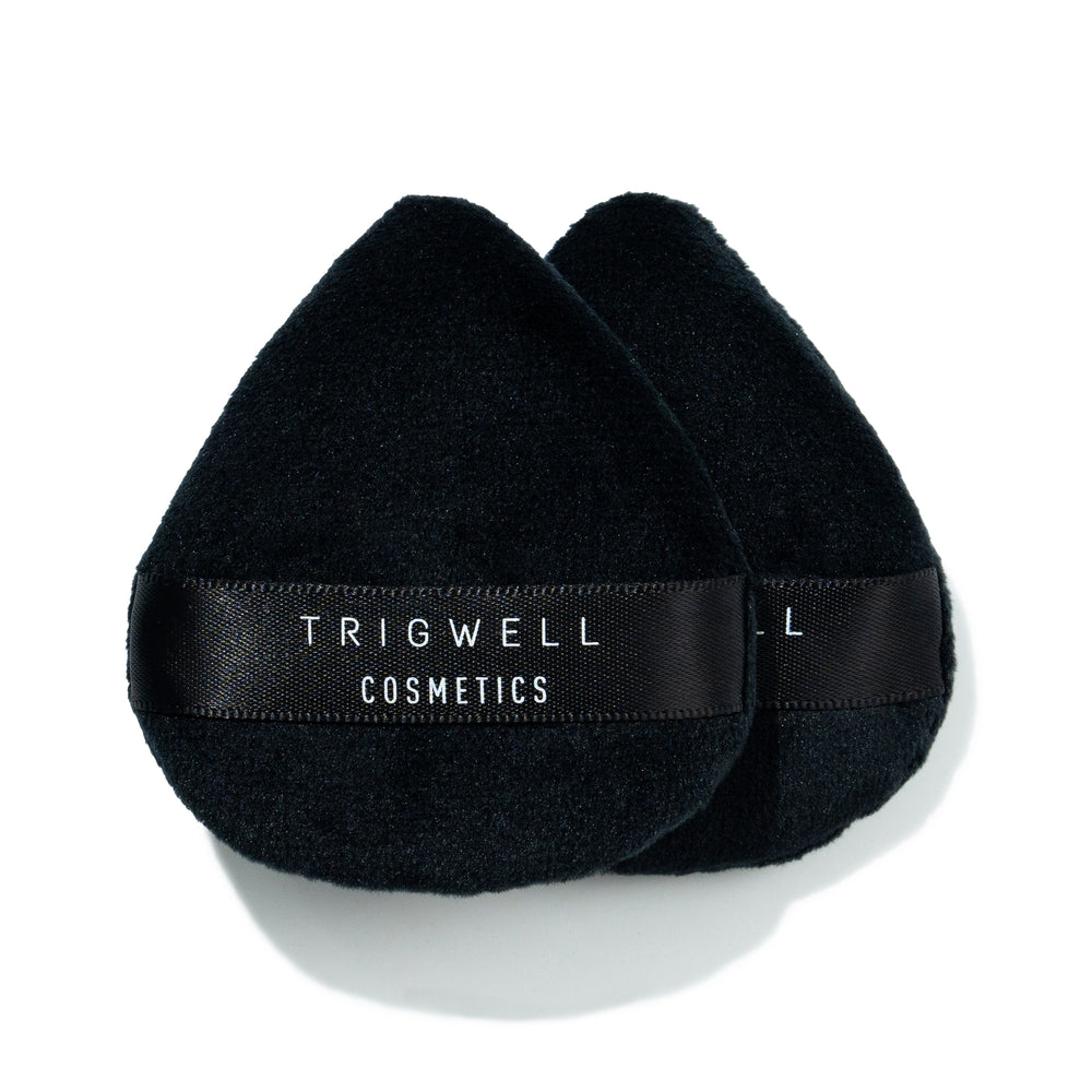 two mini powder puffs with brand name 'Trigwell Cosmetics' printed in white text on the black ribbon of the powder puff 